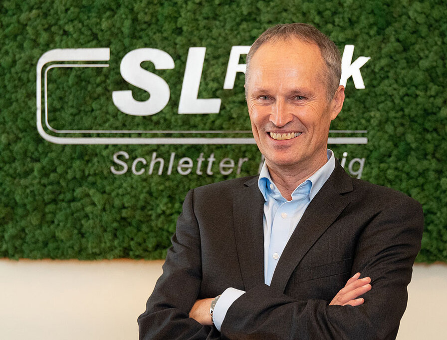 [Translate to English:] Portrait Ludwig Schletter vor Mooswand mit SL Rack Logo